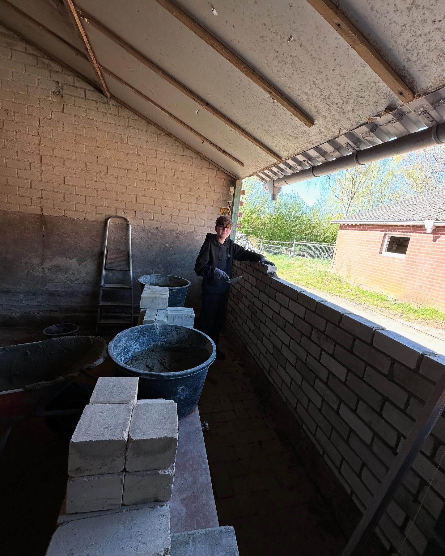 Een binnenmuur wordt gemetseld onder de overkapping